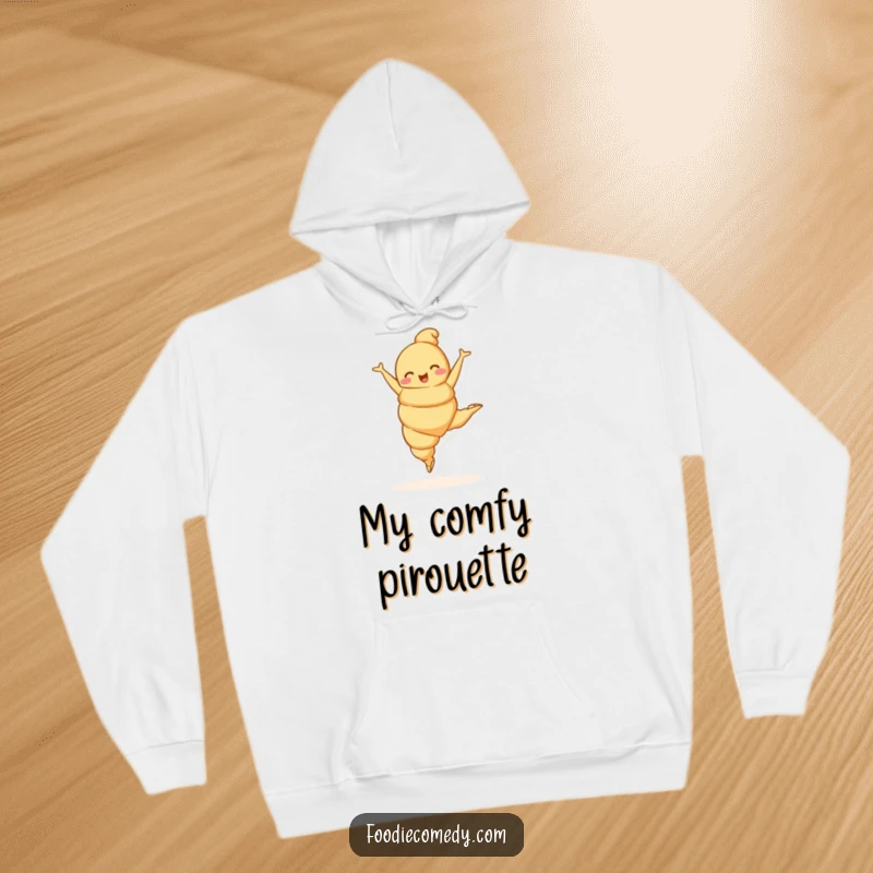 Funny croissant character performing a ballet leap on a cozy hoodie, combining warmth with artistic humor.
